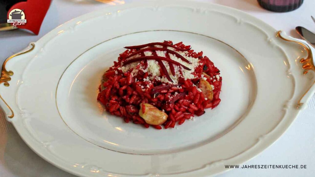 Auf einem weißen Teller ist eine Portion Rote Bete-Risotto mit Maronen angerichtet