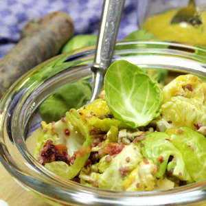 Entblätterte Rosenkohlröschen sind in einer Glasschlüssel mit Bulgur, Haselnüssen und Sonnenblumenkerne angerichtet.