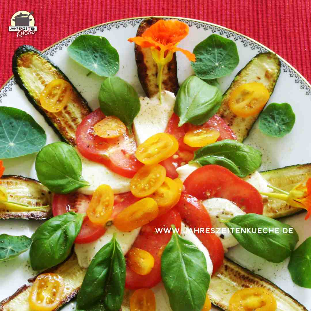Tomate, gegrilte Zucchini, Mozzarella sind mit frischen Basilikumblättern bestreut