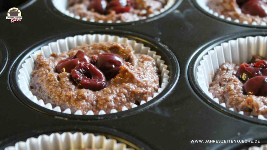 Schokoladenteig mit Kirschen in Muffinförmchen