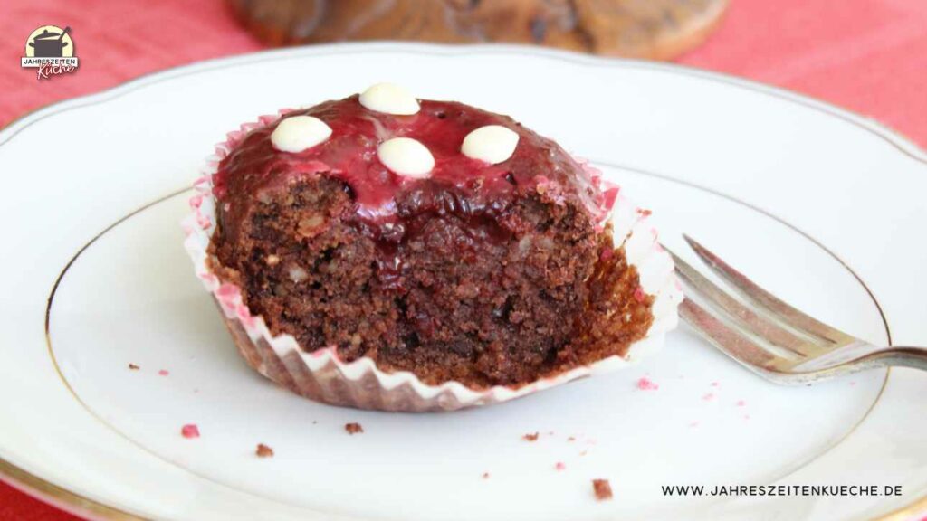 Neben einem halb aufgegessenen Kirsch-Schoko-Muffin auf liegt eine Kuchengabel