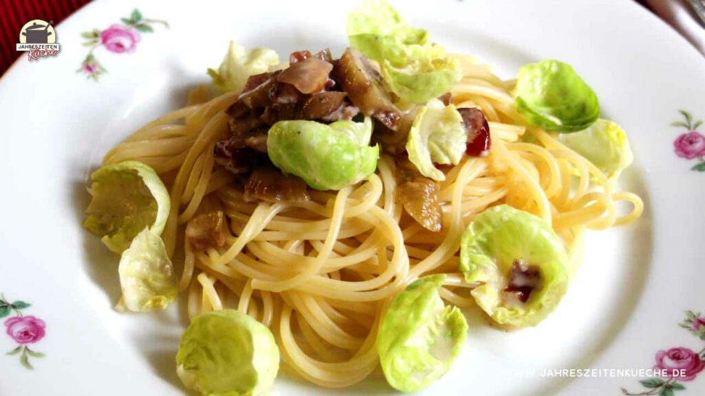 Eine Portion Spaghetti mit entblättertem Rosenkohl und Maronen auf einem Teller.