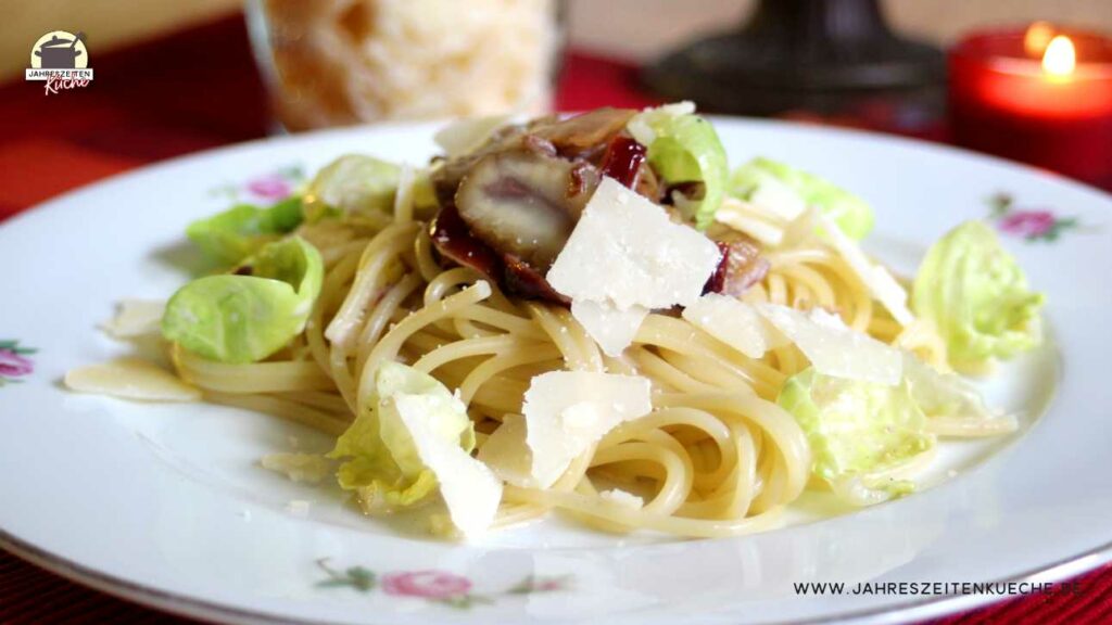 Spaghetti mit Maronen, Cranberry und gehobeltem Parmesan auf einem Teller mit Rosenmuster