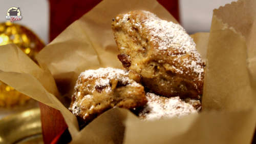 Mit Puderzucker bestreutes Stollenkonfekt liegt auf einem Backblech