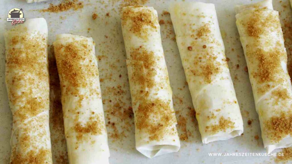 Mit Muscovadozucker bestreute Börekröllchen liegen auf einem Backblech