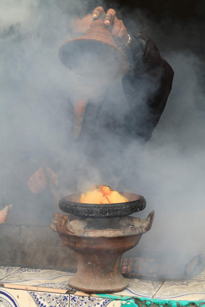 Eine Tajine mit Gemüse gart auf einem Holzkohlenfeuer.