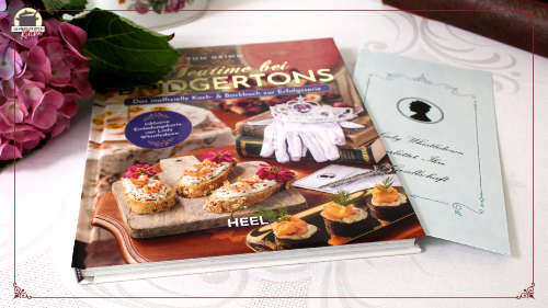 Links neben dem Buch Teatime bei Bridgertons von Tom Grimm liegt eine große Hortensienblüte