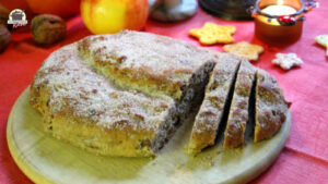 Auf einem Holzbrett liegt ein angeschnittener Christstollen mit Marzipan und Datteln
