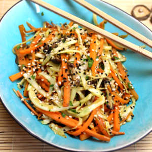 Karotten, Weißkohl und Shiitakepilze aus dem Wok sind in einer ovalen Schale angerichtet. Darüber liegt ein paar Essstäbchen.