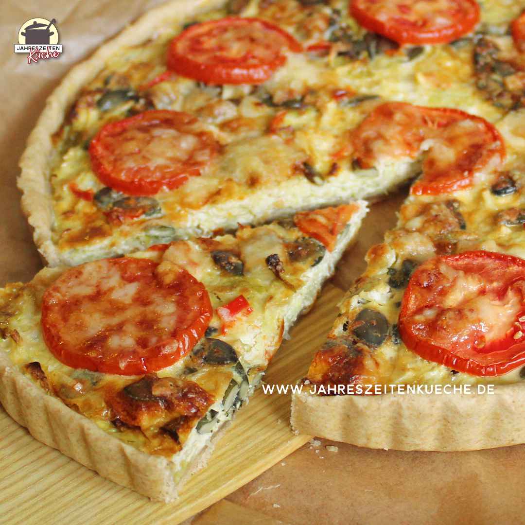 Angeschnittene Wirsingquiche, von der ein Stück auf einem Holzschieber liegt.