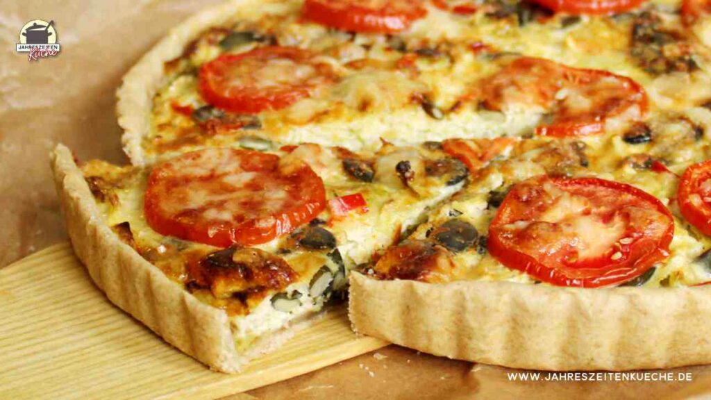 Angeschnittene Wirsingquiche, von der ein Stück auf einem Holzschieber liegt.