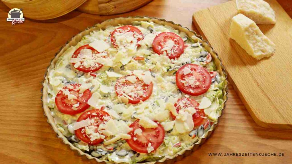 Belegter Quicheteig mit Wirsingkohl Kürbiskerne, Tomaten und gehobeltem Parmesan.