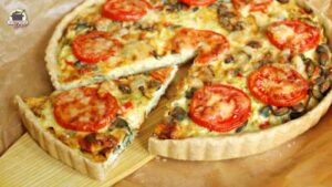 Eine angeschnittene Wirsingquiche, von der ein Stück herausgehoben wird.