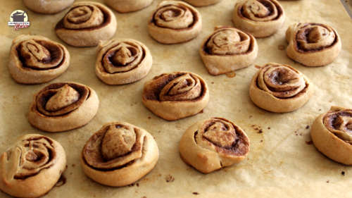 Frisch gebackene Zimtschnecken liegen auf Backpapier