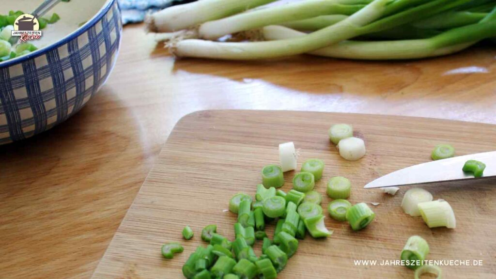 geschnittene Frühlingszwiebeln für Frühlingszwiebelpasteten auf einem Holzbrett