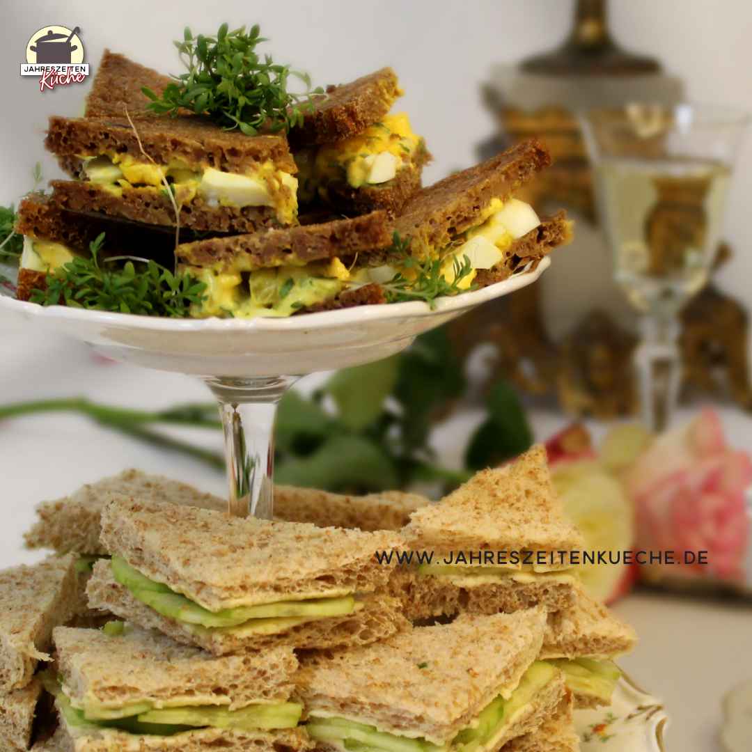 Auf einer Etagere liegen Gurkensandwiches und Ei-Kresse-Sandwiches.