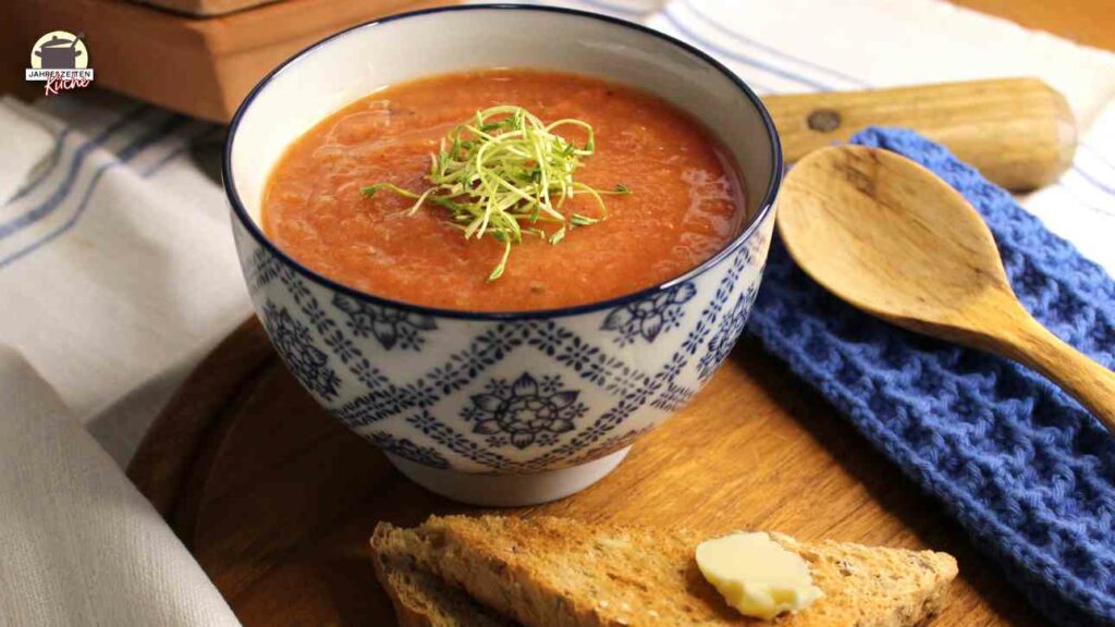 Auf einem Holzbrett steht eine Schale Pastinakensuppe mit Zimt. Danaben liegen ein Holzlöffel und Buttertoast