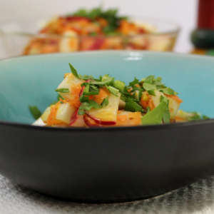 In einer türkisfarbenen Bowl ist eine Portion Mairübchen-Salat mit Grün bestreut.