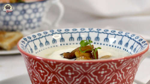 Eine Tasse mit Spargelcremesuppe, auf der gebratene Kräuterseitlinge sind