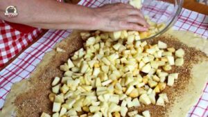 Apfelstücke werden auf dem Strudelteig verteilt