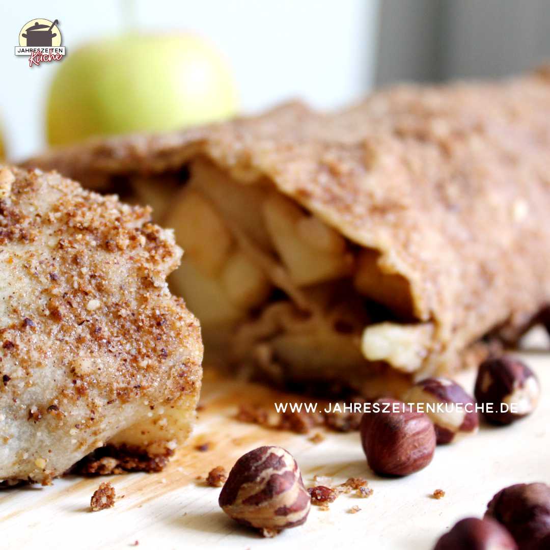 Ein gebackener Apfelstrudel liegt auf einem Holzbrett