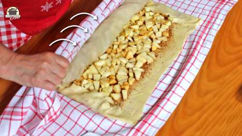 Mithilfe eines Leinentuchs wird der Strudelteig eingerollt