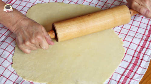 Strudelteig wird mit einer Teigrolle ausgerollt