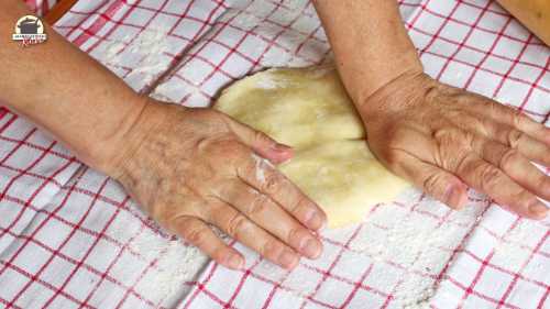Strudelteig, der auf einem Leinentuch liegt, wird mit den Händen flach gedrückt