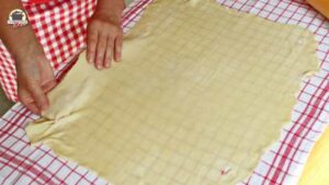 Ausgerollter Strudelteig wird glatt auf einem Leinentuch ausgelegt