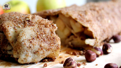 Ein gebackener Apfelstrudel liegt auf einem Holzbrett