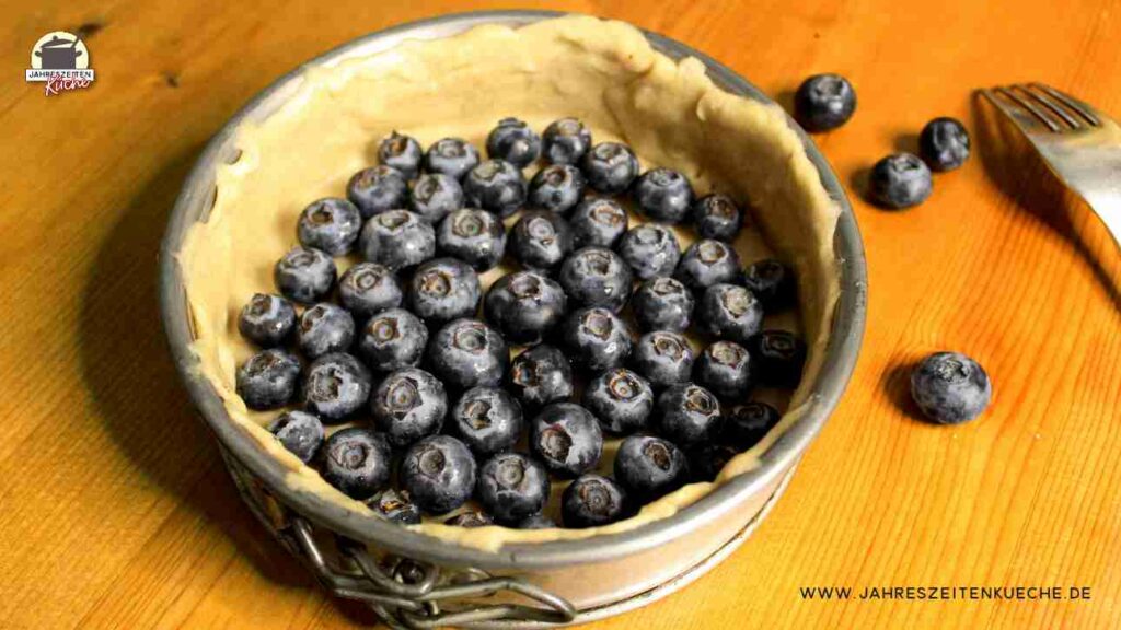 Der Teig in einer Springform ist mir frische Heidelbeeren belegt