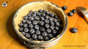 Der Teig in einer Springform ist mir frische Heidelbeeren belegt