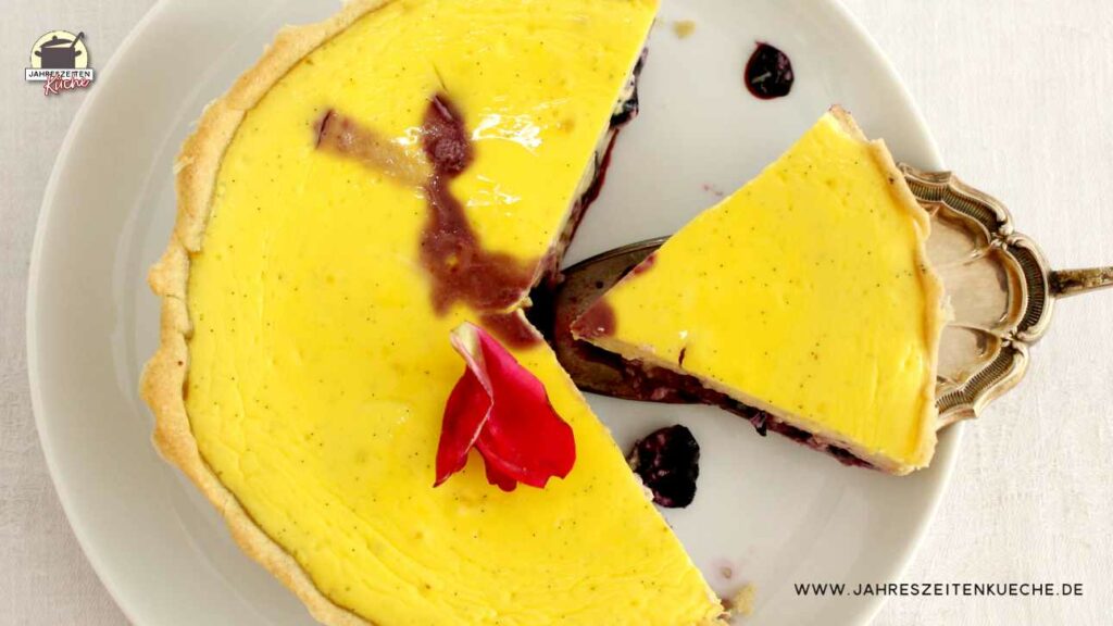 Draufsicht auf einen Heidelbeer-Käsekuchen, von dem ein Stück fehlt und ein weiteres Stück auf einem Tortenheber liegt