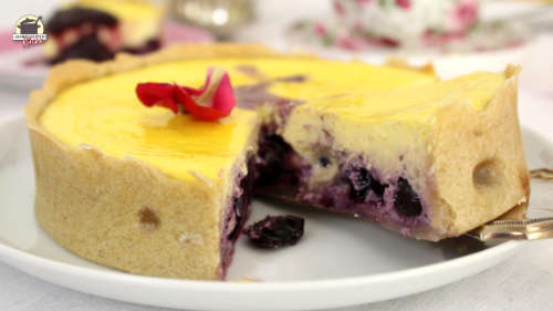 Ein Stück Käsekuchen mit Heidelbeeren wird mit einem Tortenheber vom Kuchenteller gehoben