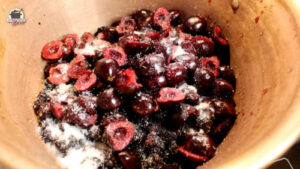 Ein kupferner Konfitüretopf mit eingezuckern Beeren und Kirschen