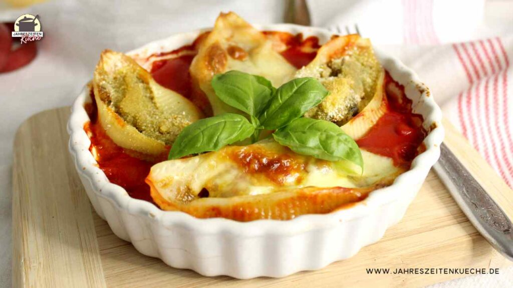 Gefüllte Conchiglioni mit Zucchini und Tomaten in Tomatensugo. Darauf liegt frisches Basilikum