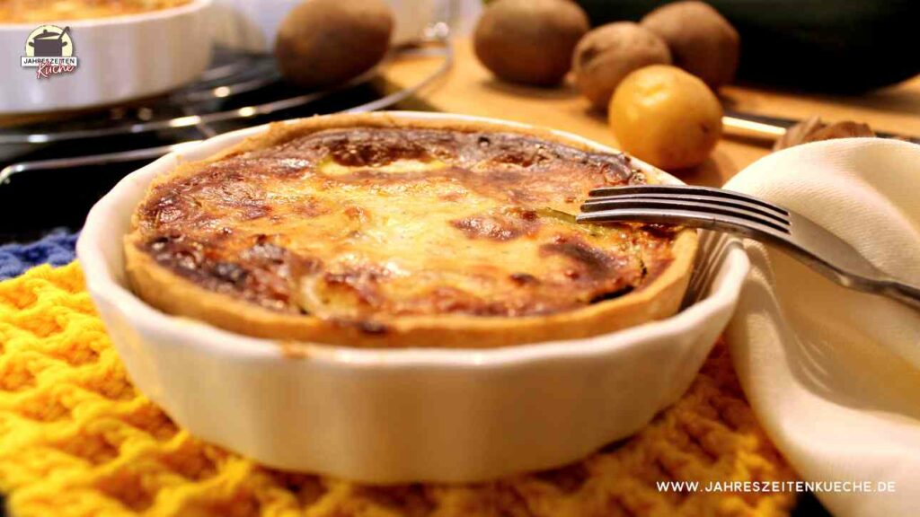 In einer Porzellanform ist eine gebackene Zucchiniquiche auf der eine Gabel liegt