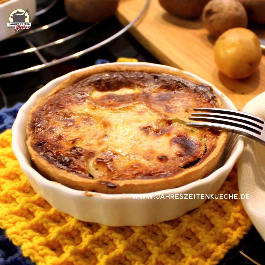 In einer Porzellanform ist eine gebackene Zucchiniquiche auf der eine Gabel liegt