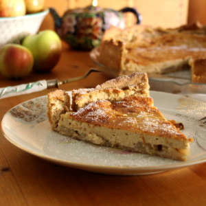 Auf einem Teller mit Goldmuster ist ein Stück Apfel-Käsekuchen.