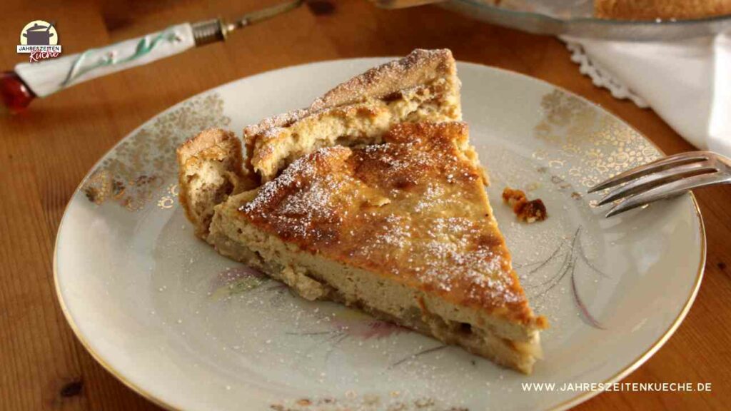 Auf einem Teller mit Goldmuster ist ein Stück Apfel-Käsekuchen.