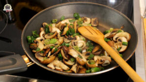 Gedünstete Champignons und Lauchzwiebeln in einer Pfanne