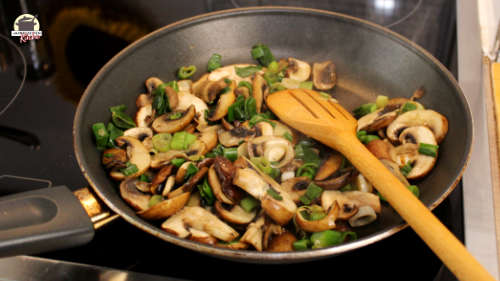 Gedünstete Champignons und Frühlingszwiebeln in einer Pfanne