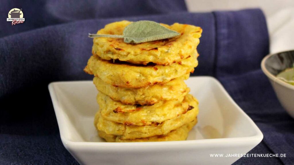 Ein Stapel Hüttenkäsepuffer auf einem kleinen Teller. Obendrauf ein Salbeiblatt