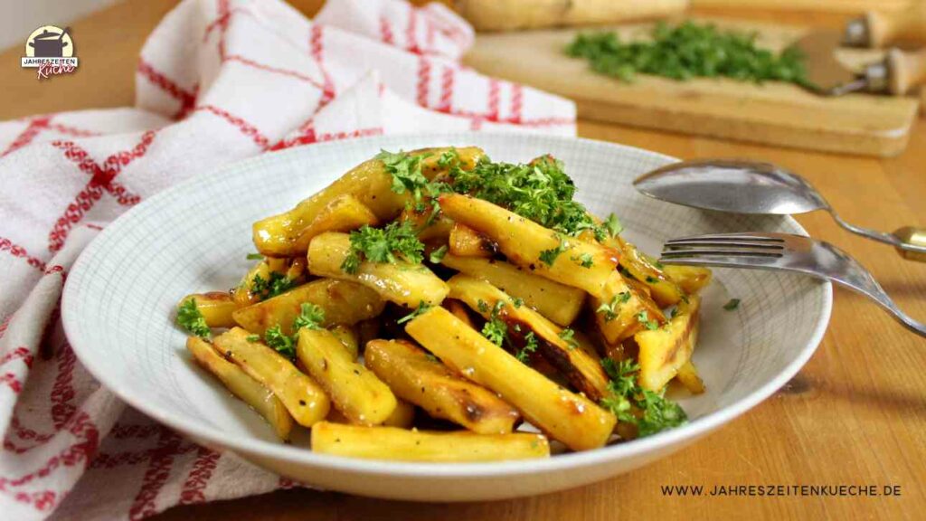 Auf einem Teller sind glasierte Pastianken mit Petersilie angerichtet. Im Hintergrund liegt ein Holzbrett mit Wiegemesser.