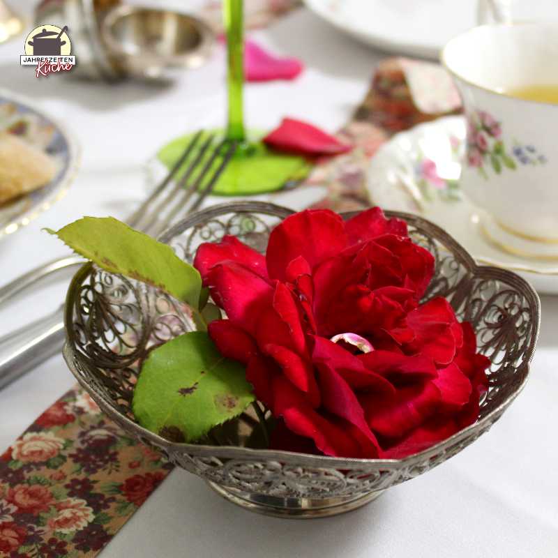 In einer filigranen silbernen Schale liegt eine rote Rose