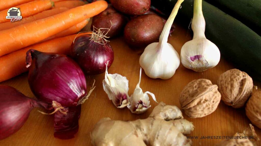 Frische Karotten Zucchini, Zwiebeln, Knoblauch und Walnüsse liegen auf einem Tisch