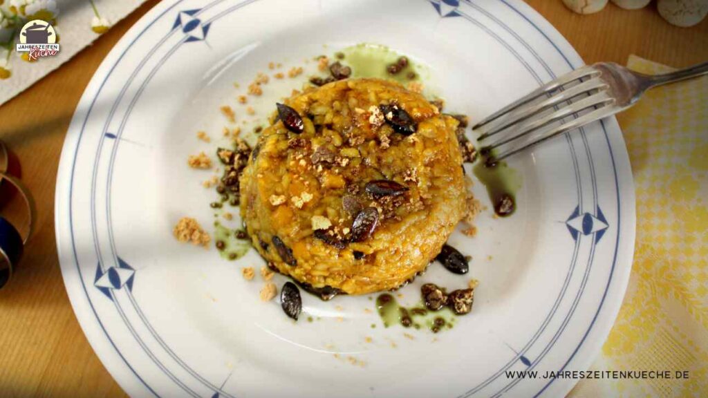Auf einem Teller mit ist eine Portion Hokkaido-Risotto mit Amaretto und Kürbiskernen angerichtet