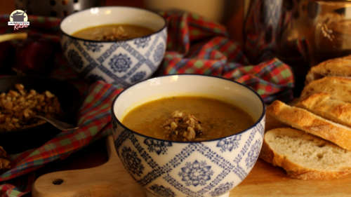 Eine Portion Karotten-Zucchini-Suppe mit Walnuss-Crunch ist in einem Schälchen angerichtet