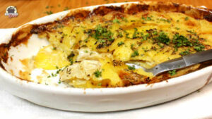 Eine ovale Auflaufform mit Kartoffel-Sellerie-Gratin dauphinois