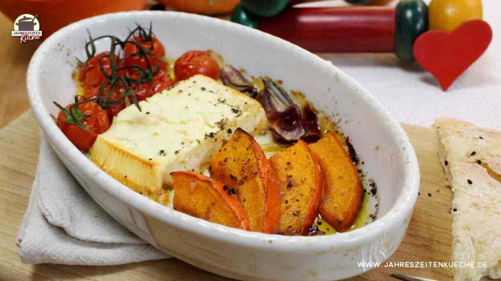 In einer weißen Keramikform liegen Kürbisspalten, Fetakäse und gegrillte Tomaten